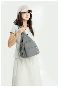 Close-up detail of the grey multi-purpose sling backpack worn by model, showing pockets and straps.