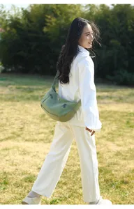 Outdoor lifestyle detail view showcasing a green casual canvas shoulder bag worn by a model.