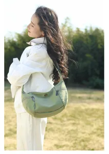 Green casual fabric shoulder bag outdoor detail view, showcasing soft texture and strap.