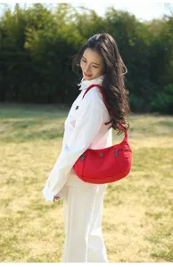 Detailed shot of a red canvas shoulder bag worn outdoors, showcasing casual style and soft fabric.