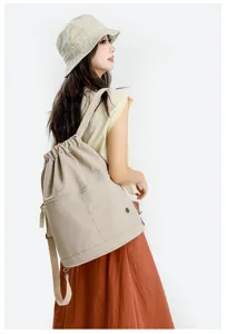 Casual beige drawstring backpack detail, stylish bucket bag worn by model for daily wear.