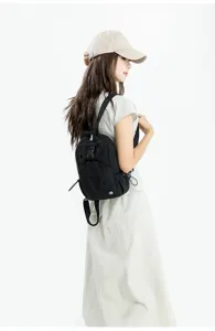 Detail view of a compact black casual backpack worn by a model, showing style and fit.