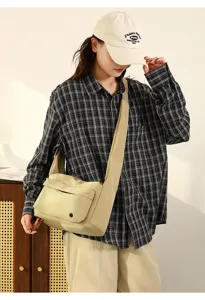 Detail view of stylish nylon crossbody messenger bag, featuring wide strap and front pocket.