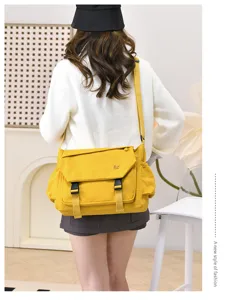 Detail view of the yellow canvas messenger bag worn by model, showing functional design and straps.