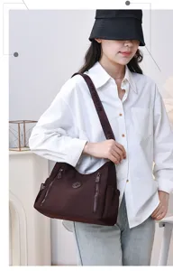 Detail view of casual nylon shoulder bag in dark brown, featuring zip pockets and sturdy strap.