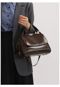Primo piano di una borsa a mano vintage in pelle PU marrone scuro con patta e dettagli.