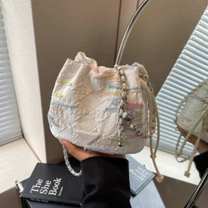 Stylish white quilted bucket bag with colorful embroidery lines, chic chain strap design detail.