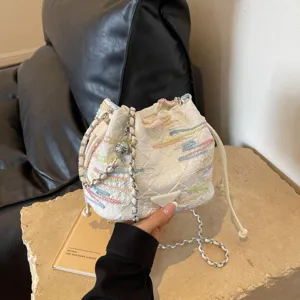 White textured bucket bag detail with colorful embroidery and chain strap for women.