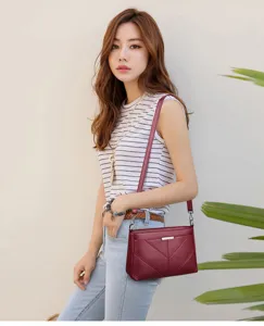 Close-up detail of the red soft leather crossbody bag worn by model, showing texture and strap.
