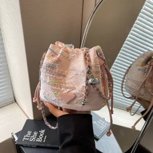 Pink woven bucket bag with stylish chain strap and iconic triangle logo for daily trendy wear.