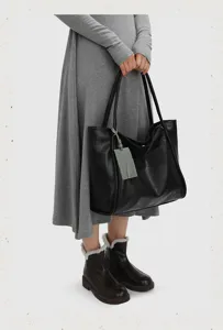Detail of a large black leather tote bag featuring shoulder straps and a chic luggage tag.
