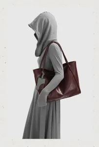 Close-up detail shot of the large red leather tote bag showing shoulder straps and grey tag.
