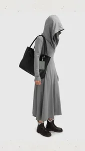Black leather tote bag shown in daily use detail, offering spacious and minimalist design.