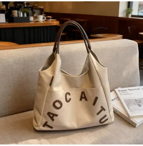 Detailed view of large capacity beige tote shoulder bag with brown handle and letter embroidery.