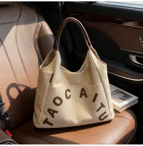 Large capacity canvas tote bag with brown leather handles and chic letter embroidery for women.