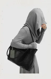 Minimalist black leather tote bag detail, featuring soft slouchy texture and dual straps.