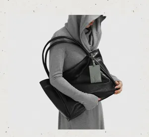 Close-up view of a large black leather tote bag, showing slouchy texture and double straps.