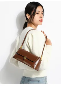 Detail view of a brown leather shoulder bag worn by a model, featuring metal lock closure.