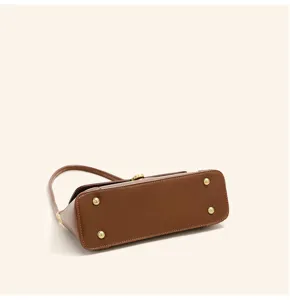 Brown leather shoulder bag bottom detail showing metal feet and hardware quality.