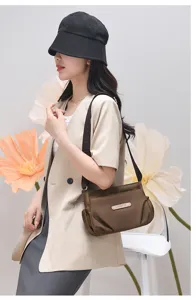 Detail view of a brown nylon casual shoulder bag worn by a model with floral background.