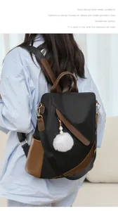 Stylisches Kontrast-Rucksack-Detail mit schwarzem Stoff, braunem Leder und flauschigem Bommel.