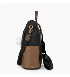 Seitenansicht des schwarz-braunen Damen-Rucksacks im Blockdesign mit Plüschball, Pendlertasche.