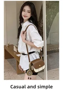 Detail view of stylish contrast color round crossbody bag with soft leather and cute charm.