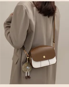 Detail shot of women's contrast color mini cross-body shoulder bag with cute fluffy charm.