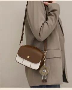 Detailed view of the stylish brown and white color-block crossbody bag with cute furry pendant.