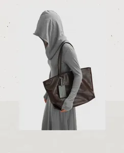 Detail view of large capacity soft leather tote bag in dark brown with elegant grey tag.