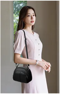 Detailed view of the stylish black leather crossbody bag worn by model in lifestyle setting.