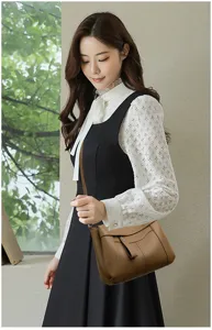 Detailed view of elegant brown leather shoulder bag worn by model in chic daily outfit.