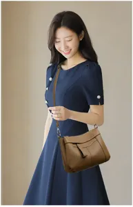Detailed view of the stylish brown leather crossbody shoulder bag worn by an elegant model.