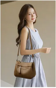 Close-up detail of the brown leather shoulder bag worn by the model, showing strap and flap.
