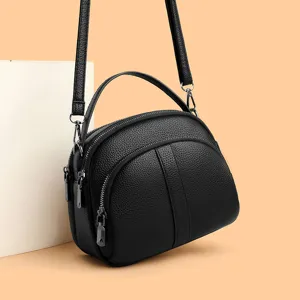 Elegant black leather crossbody bag with top handle and multiple zipper compartments for women.
