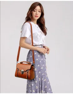 Vintage brown leather crossbody shoulder bag with metal lock and handle in the scene.
