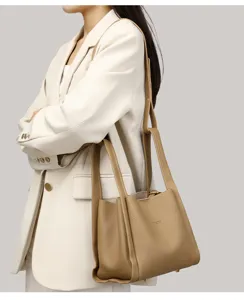 Vista detallada del elegante bolso bombonera de cuero caqui con doble correa llevado.