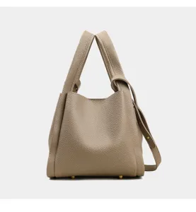 Detalle del bolso cubo de cuero minimalista con textura fina y pies metálicos.