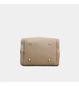 Vista detallada del fondo de elegante bolso cruzado de cuero con pies metálicos protectores.