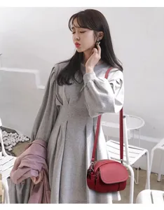 Close-up view of the stylish red mini crossbody bag worn in a chic indoor cafe scene.