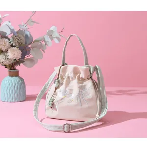 Detailed view of Chinese style embroidered bucket bag with delicate floral pattern and green strap.
