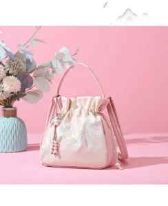 Chic embroidered bucket bag with delicate floral details and charming wooden bead accents.