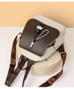 Nahaufnahme des schicken zweifarbigen Rucksacks mit süßem Bärenanhänger und Reißverschluss.