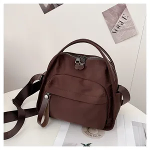 Detailed view of casual brown nylon crossbody bag with dual top handles and zippers.