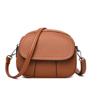 Close-up detail of the brown leather mini bag showing textured finish and metal parts.