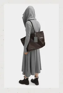 Close-up view of the large capacity soft leather tote bag in dark brown showing shoulder carry.