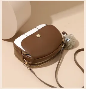 Close-up detail of the brown and white color-block crossbody bag with metal flower accent.