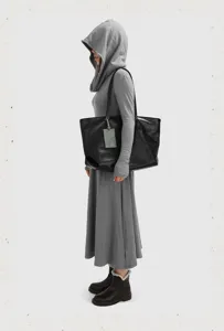 Detail view of large capacity black soft leather tote bag worn by model, ideal for daily commuting.