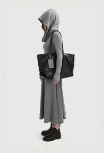 Detailed shot of a large soft leather black tote bag with slender straps and tag accent.