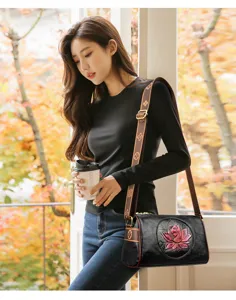 Vintage black barrel shoulder bag with lotus embossed patch and chic patterned strap for women.